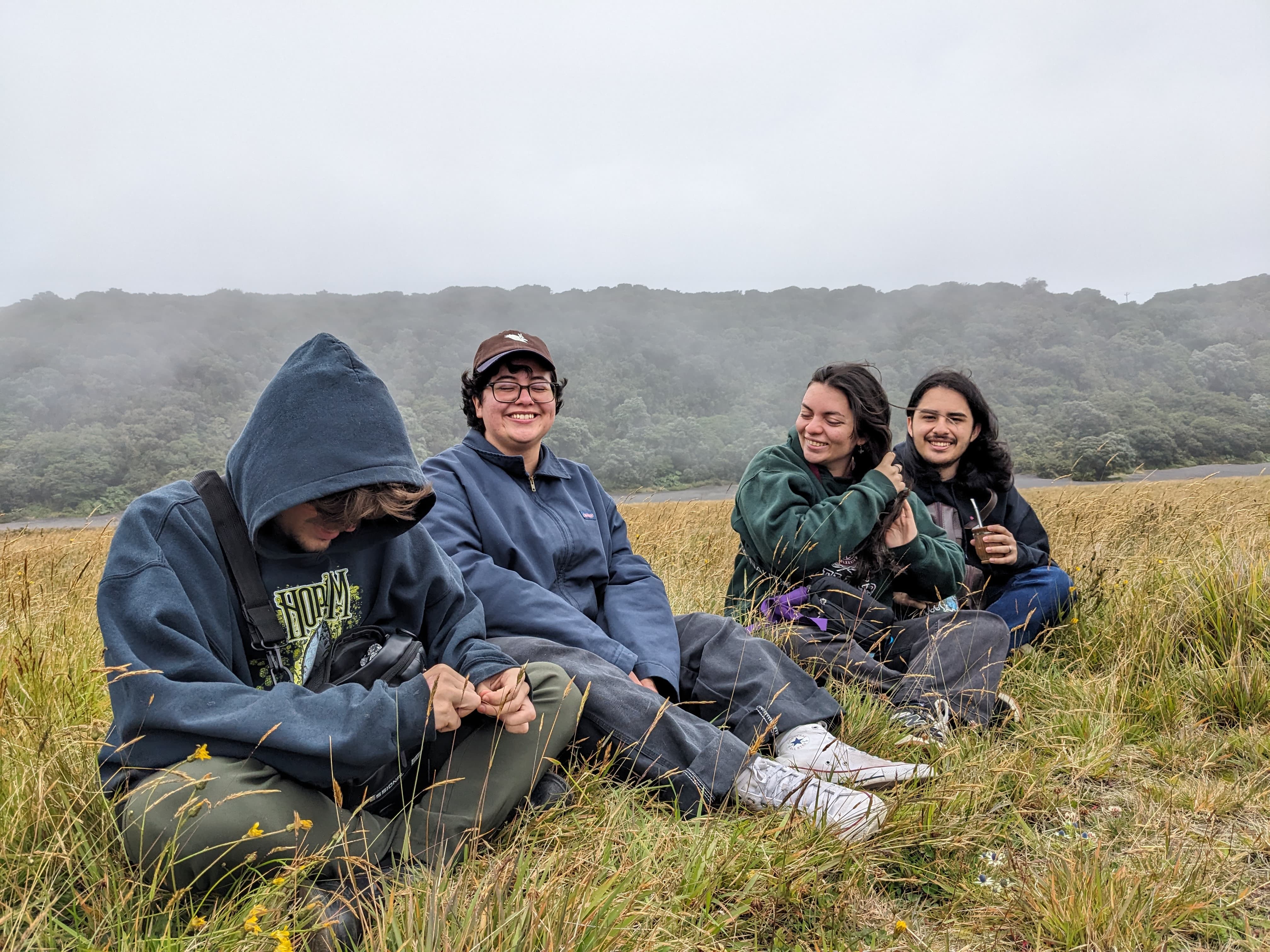 Emilio smiling while sitting on a patch of grass in Irazu Volcano National Park with his friends.